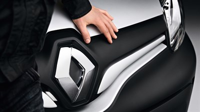 A hand placed on a Renault car near its logo